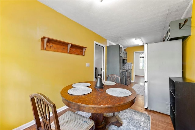 dining area with wood finished floors, baseboards, and a textured ceiling