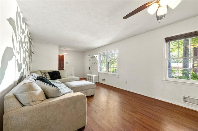 living area featuring wood-type flooring, ceiling fan, and baseboards