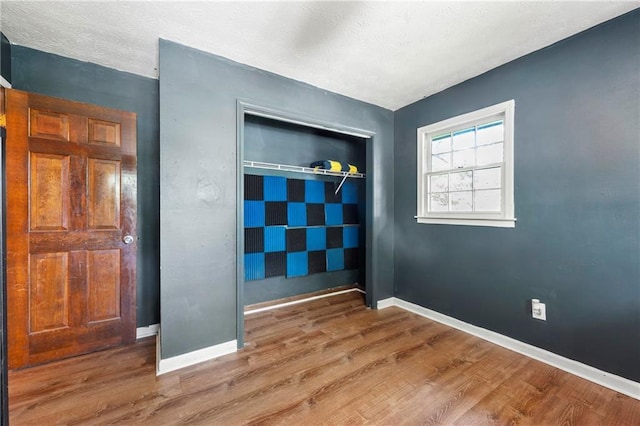 unfurnished bedroom with wood finished floors, a closet, and baseboards