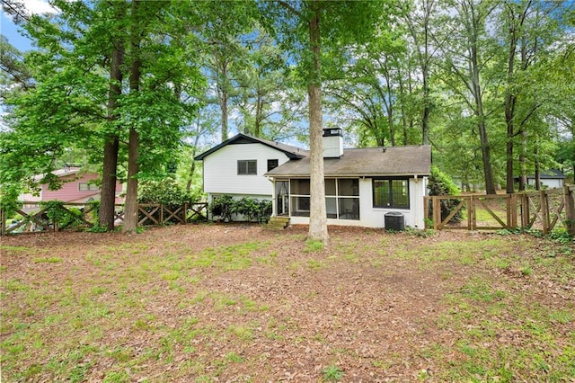 rear view of house with a sunroom, a fenced backyard, a chimney, and a gate