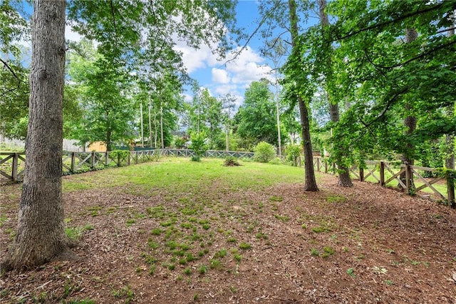 fenced backyard with view of scattered trees