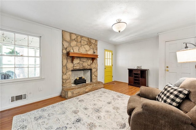 living area featuring baseboards, wood finished floors, ornamental molding, and a fireplace