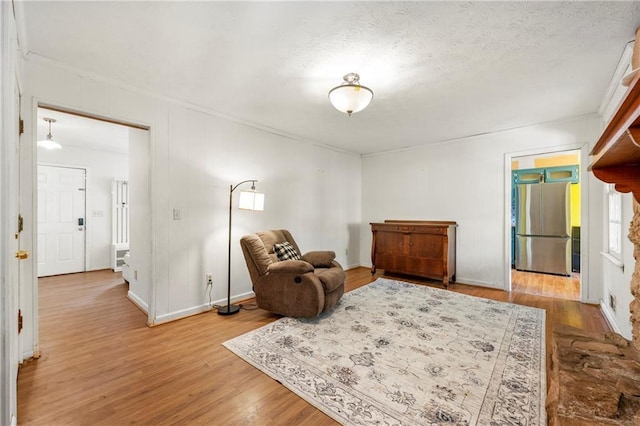 living area featuring wood finished floors, a textured ceiling, and baseboards