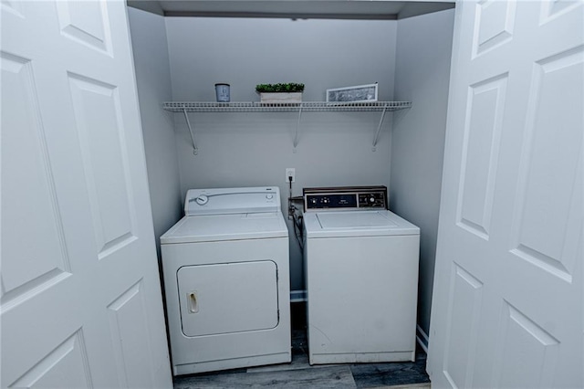 clothes washing area with independent washer and dryer, wood finished floors, and laundry area