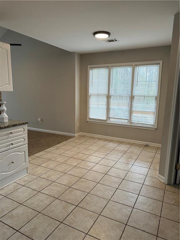 unfurnished room with light tile patterned floors, visible vents, and baseboards