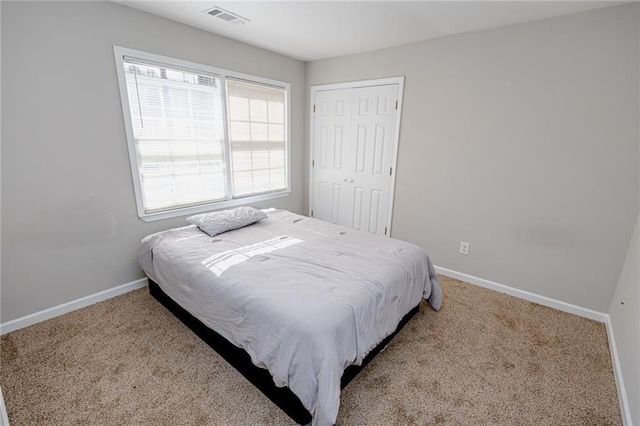 carpeted bedroom featuring baseboards, visible vents, and a closet