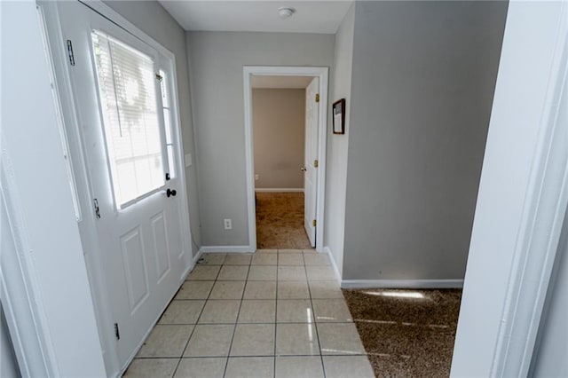 entryway featuring light tile patterned flooring, light colored carpet, and baseboards