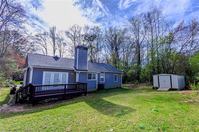 back of property featuring a storage unit, an outbuilding, french doors, a yard, and a chimney