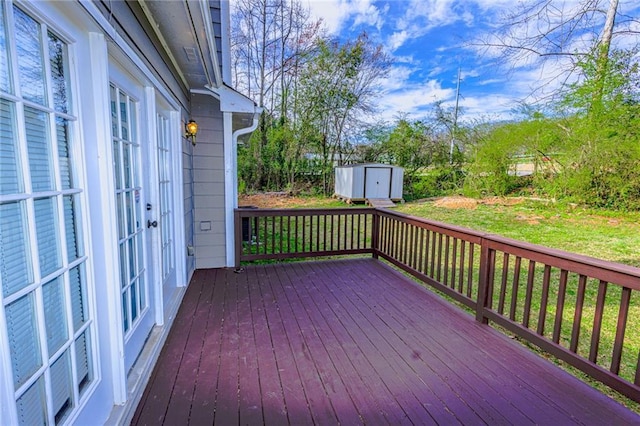 wooden terrace featuring a storage shed, a yard, an outbuilding, and french doors