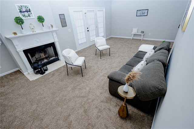 living area featuring baseboards, a fireplace with flush hearth, and carpet flooring