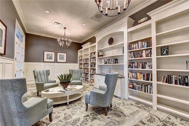 sitting room featuring a notable chandelier, crown molding, and built in shelves