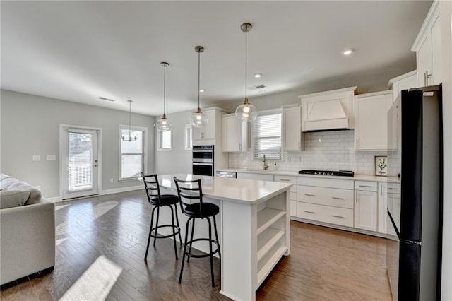 kitchen with premium range hood, white cabinets, plenty of natural light, and a center island