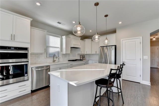 kitchen with a center island, sink, dark hardwood / wood-style floors, appliances with stainless steel finishes, and white cabinetry