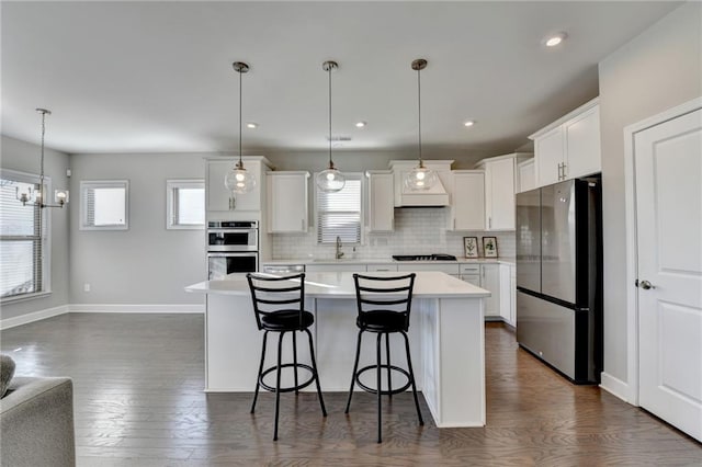 kitchen featuring pendant lighting, a kitchen island, white cabinetry, and appliances with stainless steel finishes