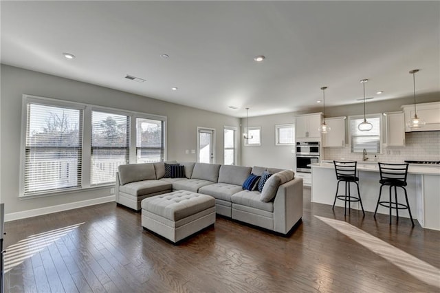 living room with a wealth of natural light, dark wood-type flooring, and sink