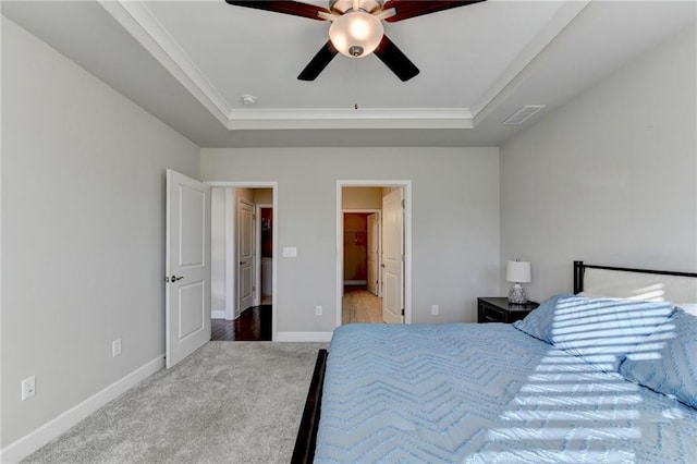 carpeted bedroom with ceiling fan and a tray ceiling