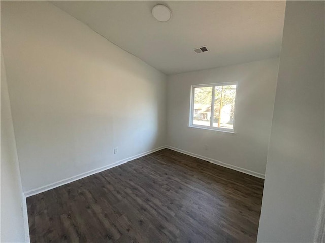 empty room with baseboards, visible vents, and dark wood-style flooring