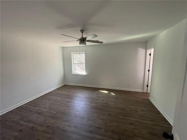 spare room featuring a ceiling fan, dark wood-style flooring, and baseboards