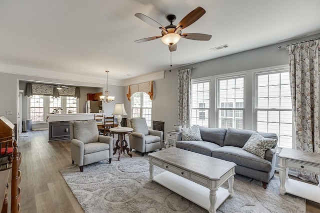 living area featuring ceiling fan with notable chandelier, visible vents, and wood finished floors