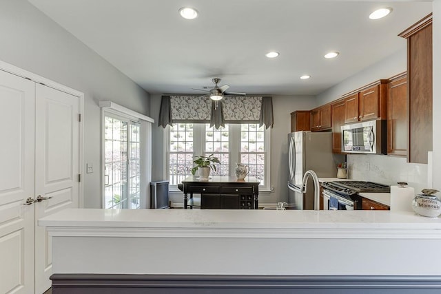 kitchen with brown cabinetry, ceiling fan, light countertops, appliances with stainless steel finishes, and recessed lighting