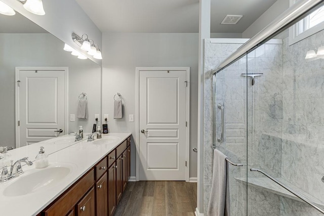 full bath featuring visible vents, wood finished floors, a shower stall, and a sink