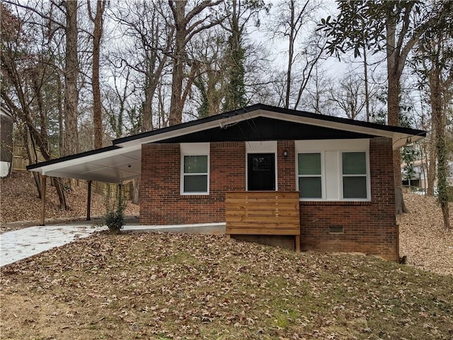 view of front of house with concrete driveway, crawl space, covered porch, a carport, and brick siding