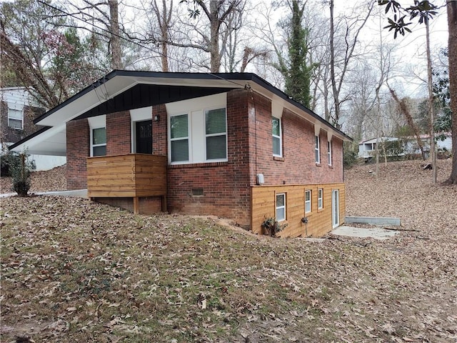 view of side of property with crawl space and brick siding