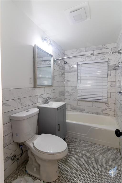 full bath with toilet,  shower combination, vanity, and tile walls