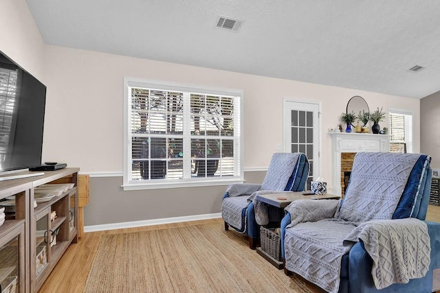 living area featuring light wood finished floors, baseboards, and visible vents