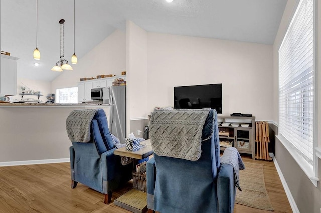 living room with light wood-type flooring, high vaulted ceiling, baseboards, and a notable chandelier