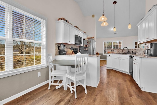 kitchen featuring baseboards, stainless steel fridge with ice dispenser, wood finished floors, a peninsula, and white cabinetry