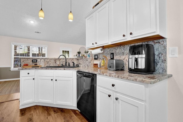 kitchen featuring backsplash, a sink, wood finished floors, dishwasher, and a peninsula