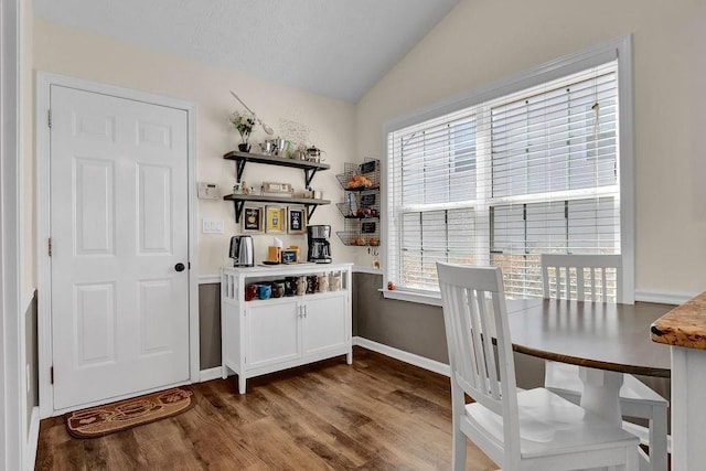 dining room featuring baseboards, vaulted ceiling, and wood finished floors