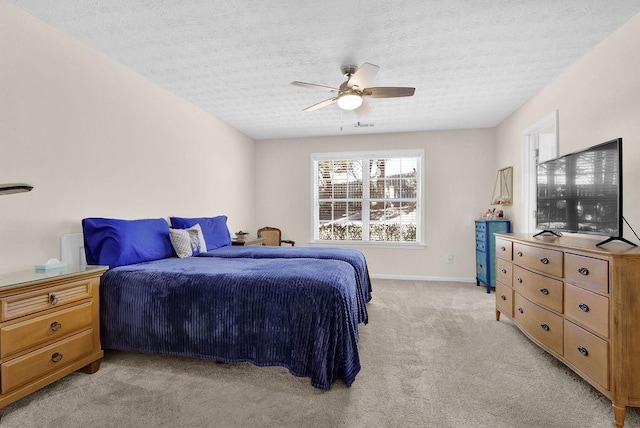 bedroom with ceiling fan, baseboards, a textured ceiling, and light colored carpet