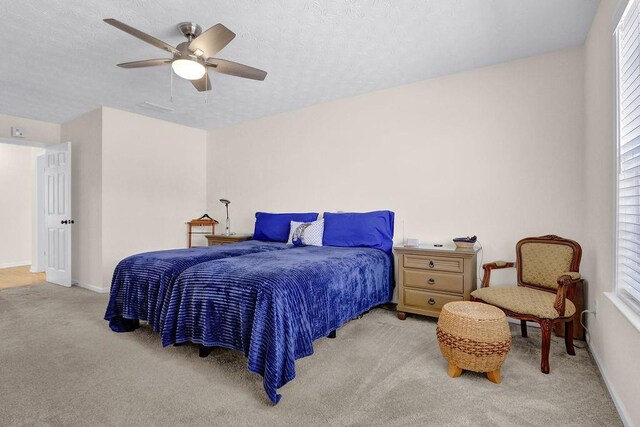 carpeted bedroom featuring a textured ceiling, baseboards, and a ceiling fan