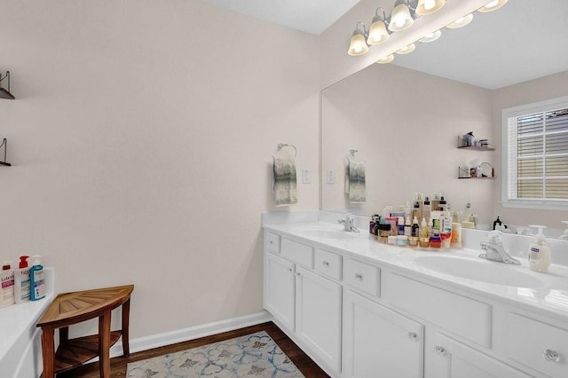 full bath featuring wood finished floors, a sink, baseboards, and double vanity