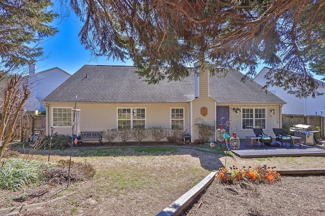 ranch-style house featuring a chimney, fence, a deck, and roof with shingles