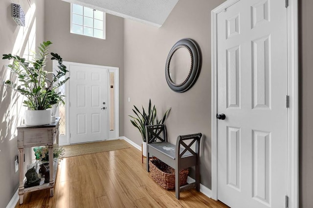 entrance foyer featuring light wood-type flooring, a high ceiling, and baseboards