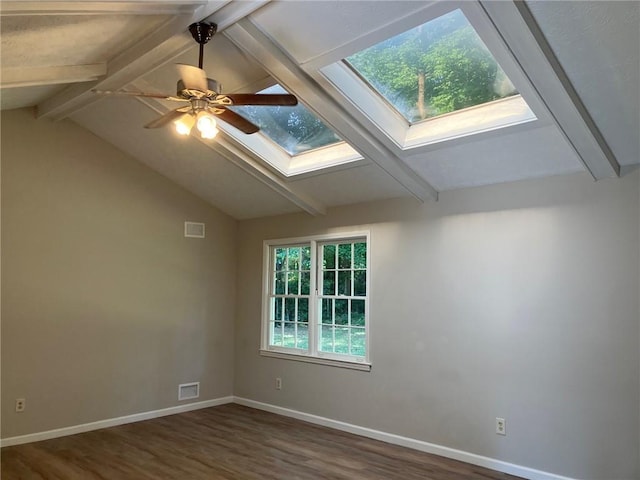 empty room featuring lofted ceiling with skylight, dark hardwood / wood-style floors, and ceiling fan