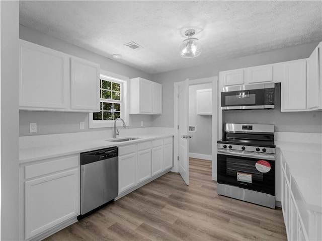220 Sugar Hill Ct, Jackson, GA 30233 - kitchen featuring appliances with stainless steel finishes, a sink, white cabinetry, a textured ceiling, and light countertops