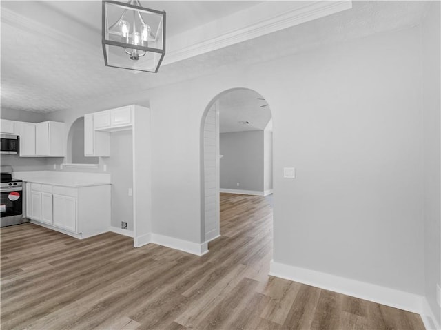 220 Sugar Hill Ct, Jackson, GA 30233 - kitchen featuring appliances with stainless steel finishes, arched walkways, white cabinetry, light wood finished floors, and a textured ceiling