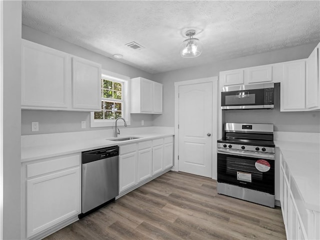 220 Sugar Hill Ct, Jackson, GA 30233 - kitchen with appliances with stainless steel finishes, a sink, white cabinetry, a textured ceiling, and light countertops