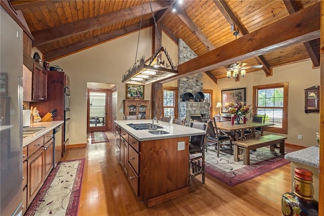 259 Eagle Chase Cir, Dillard, GA 30537 - kitchen featuring a wood ceiling with exposed beams, a fireplace, light wood finished floors, a kitchen island with sink, and a ceiling fan
