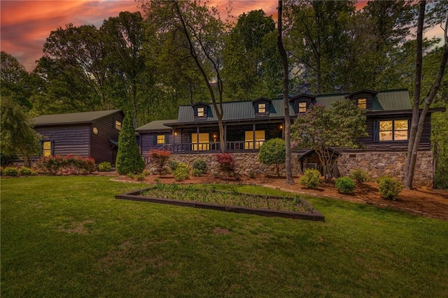 259 Eagle Chase Cir, Dillard, GA 30537 - back of property at dusk featuring stone siding, a yard, covered porch, and a metal roof