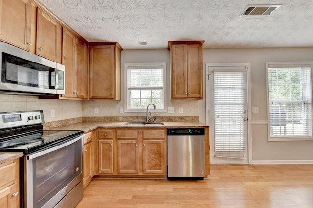 kitchen with a healthy amount of sunlight, light hardwood / wood-style floors, sink, and appliances with stainless steel finishes