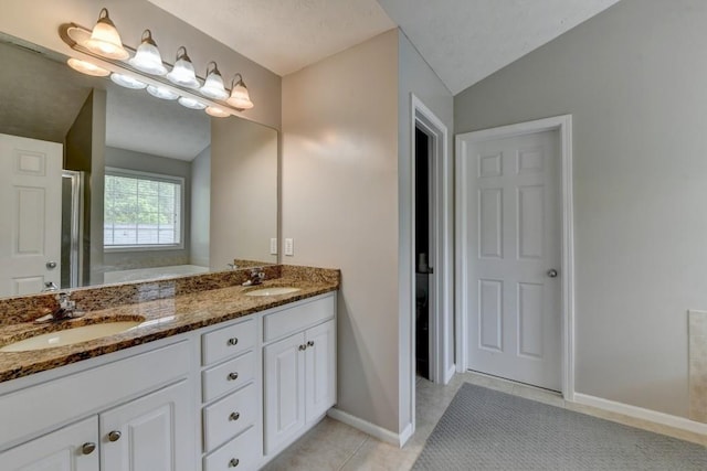 bathroom with tile patterned floors, vanity, vaulted ceiling, and walk in shower