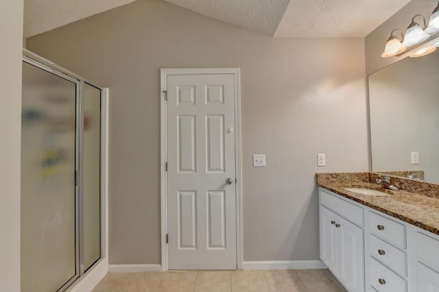 bathroom with walk in shower, tile patterned flooring, a textured ceiling, vaulted ceiling, and vanity