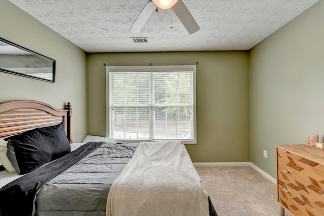 bedroom featuring ceiling fan, light carpet, and a textured ceiling