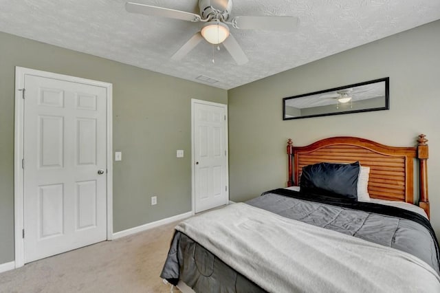 bedroom featuring light carpet, a textured ceiling, and ceiling fan