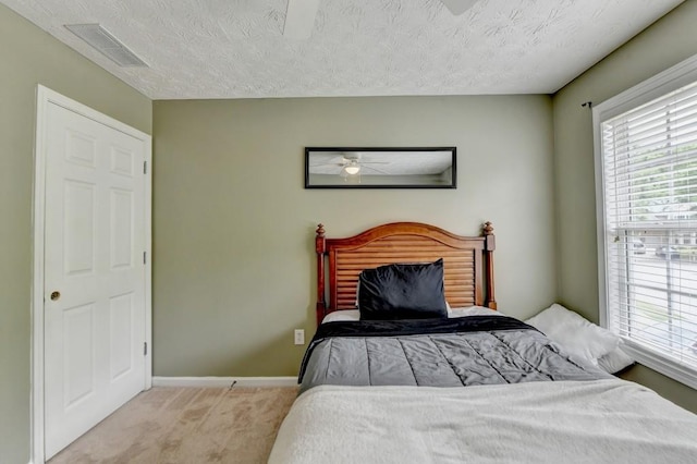 bedroom with a textured ceiling and light colored carpet